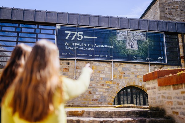 Zwei Personen zeigen auf das Plakat der Ausstellung "775 - Westfalen".