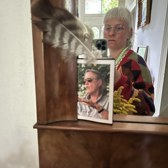 Eine Frau fotografiert sich in einem Spiegel, an dem wiederum das Foto einer anderen Frau, der Gräfin, pinnt. (vergrößerte Bildansicht wird geöffnet)