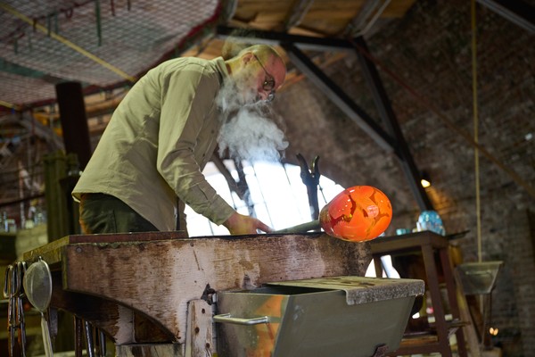 Ein Mann stellt ein Glasgefäß her.