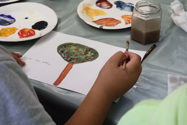 Eiine Kinderhand mit Pinsel und ein gemaltes Bild