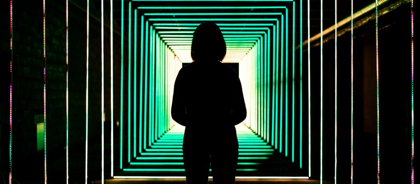 Frau vor Tunnel aus Neon-Lichtröhren in grün