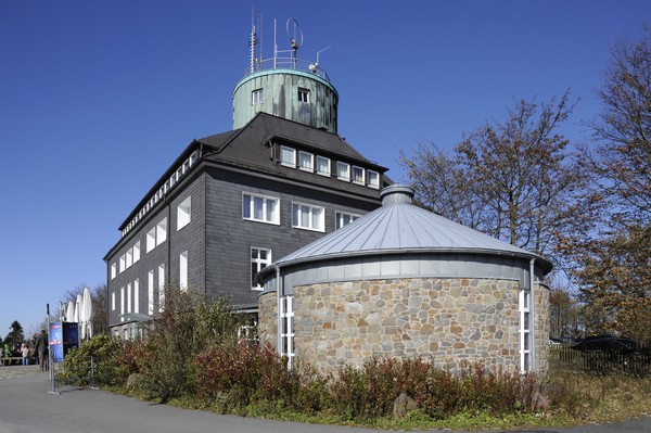 Blick von außen auf das eckige, mehrgeschössige Gebäude am Kahlen Asten mit rundem Anbau.