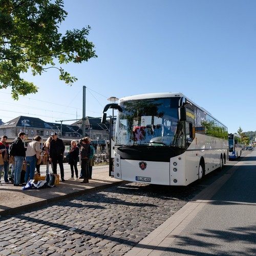 Menschen versammeln sich vor einem Reisebus, bereit für die Abfahrt.