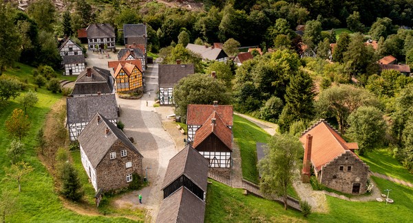 Luftaufnahme eines historischen Dorfes mit Fachwerkhäusern in einer Landschaft mit grünen Bäumen.