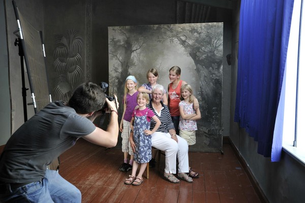 Ein Fotograf fotografiert Museumsbesucher vor dem Hintergrund einer Leinwand mit einem Waldmotiv.