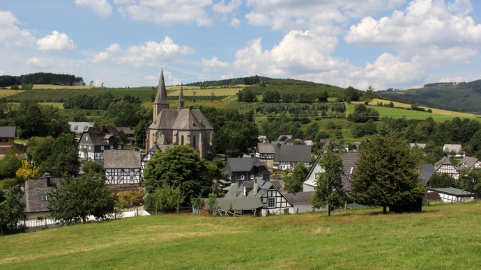 Historisches Dorf mit Kirche und Fachwerkhäusern in grüner Landschaft