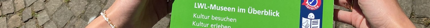 Zwei Hände halten die Gesamtbroschüre in Leichter Sprache zu den LWL-Museen